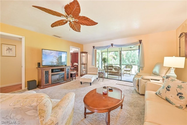 living room featuring light carpet, ceiling fan, and a fireplace