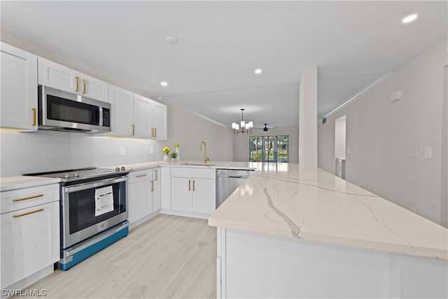 kitchen with ornamental molding, white cabinets, light hardwood / wood-style floors, and stainless steel appliances