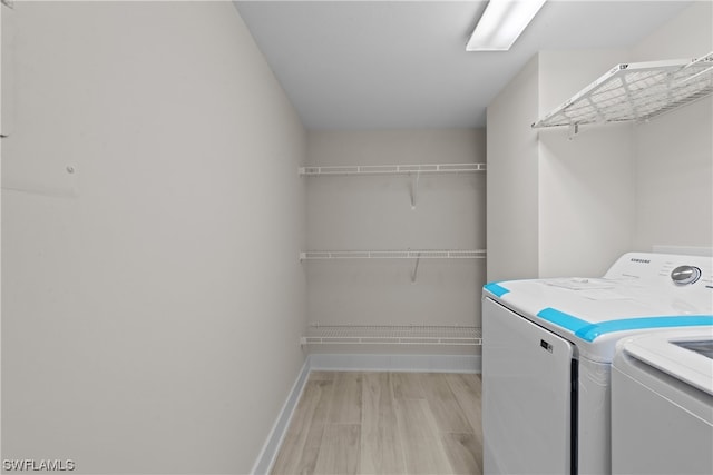 laundry room with washing machine and dryer and light hardwood / wood-style flooring