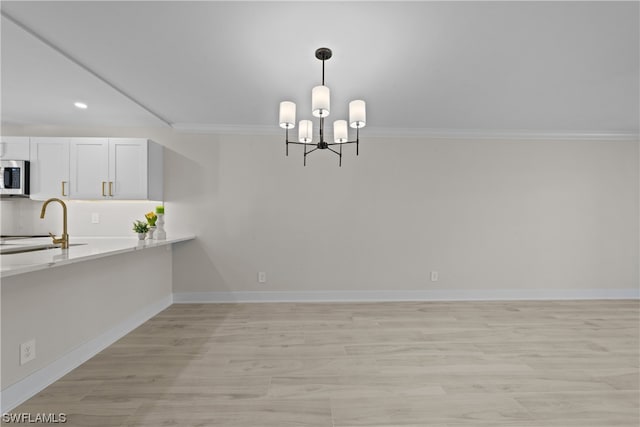 unfurnished dining area featuring a notable chandelier, sink, and light wood-type flooring