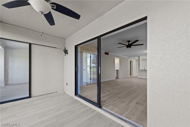 spare room with light hardwood / wood-style floors, ceiling fan, and a textured ceiling