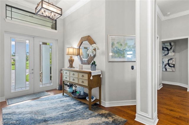 foyer entrance with dark wood-type flooring, crown molding, french doors, and a notable chandelier