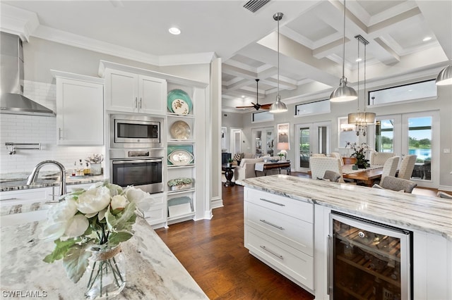 kitchen featuring beam ceiling, coffered ceiling, white cabinetry, stainless steel appliances, and beverage cooler