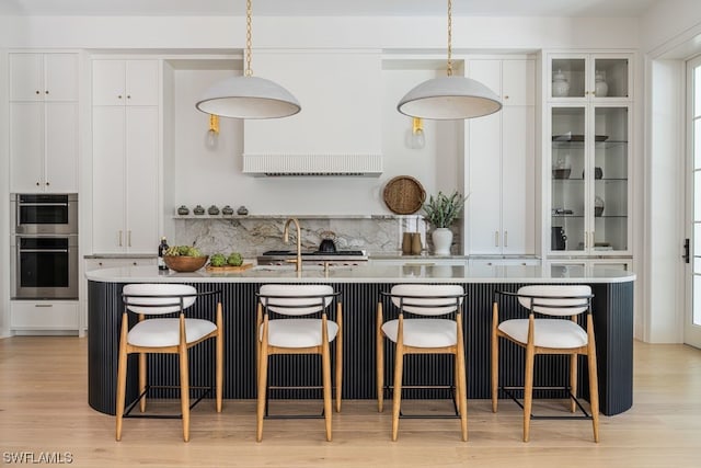 kitchen with a kitchen bar, white cabinetry, and pendant lighting