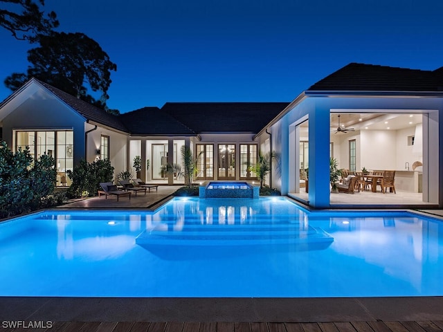 pool at twilight with an in ground hot tub, ceiling fan, and a patio