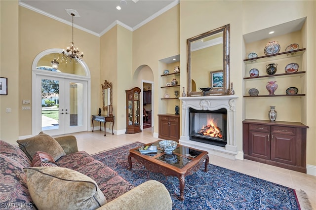 living room with built in shelves, a lit fireplace, ornamental molding, arched walkways, and light tile patterned flooring