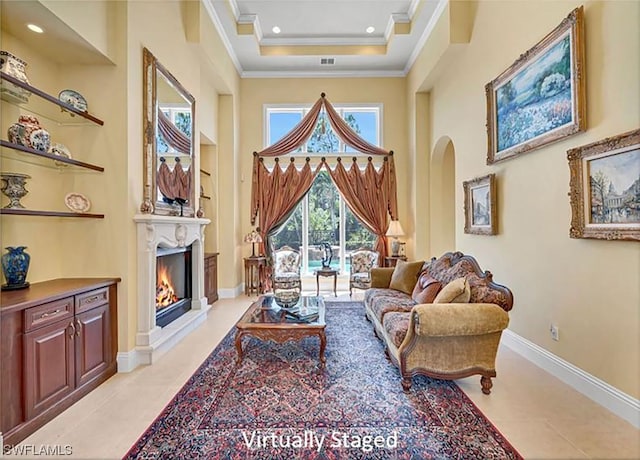 living room featuring ornamental molding, recessed lighting, a lit fireplace, baseboards, and a towering ceiling