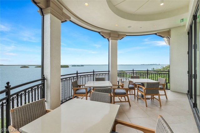 balcony featuring outdoor dining area and a water view