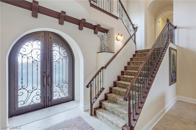 tiled entrance foyer featuring french doors and a towering ceiling