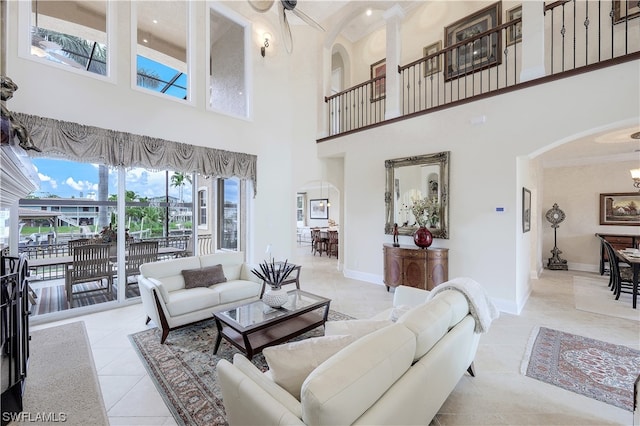 tiled living room with ceiling fan and a towering ceiling