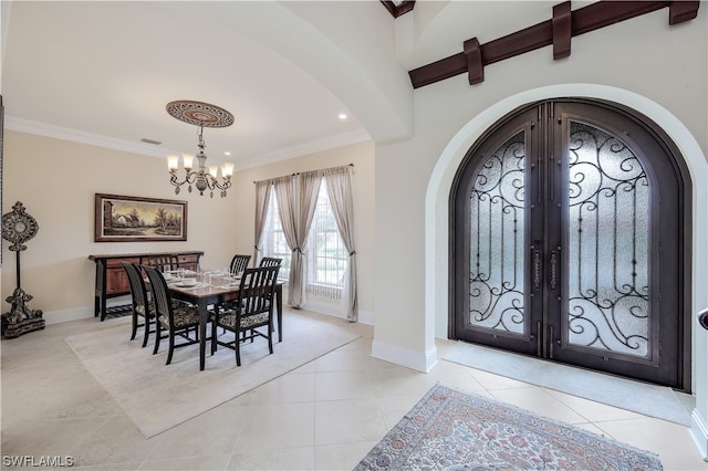 foyer entrance with light tile floors, ornamental molding, a notable chandelier, and french doors