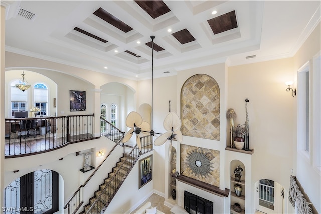 interior space with a high ceiling, coffered ceiling, crown molding, and beamed ceiling