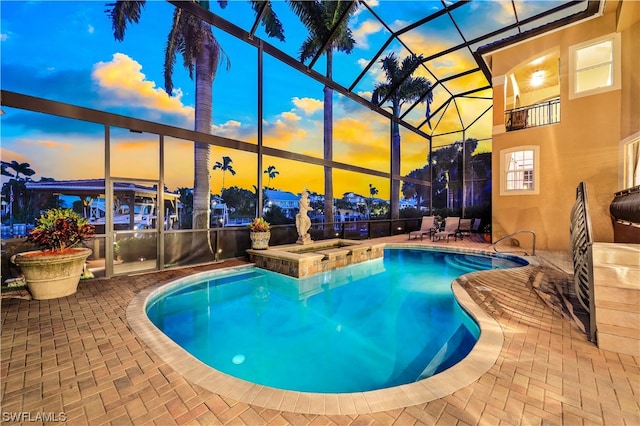 pool at dusk featuring an in ground hot tub, a lanai, and a patio