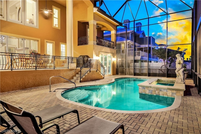 pool at dusk featuring an in ground hot tub and a patio area