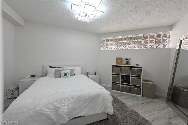 bedroom with multiple windows, a textured ceiling, and light hardwood / wood-style flooring