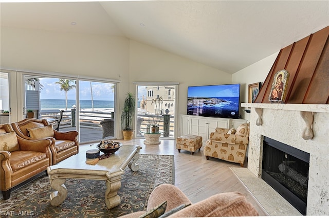 living room featuring a water view, high vaulted ceiling, light hardwood / wood-style flooring, and a premium fireplace