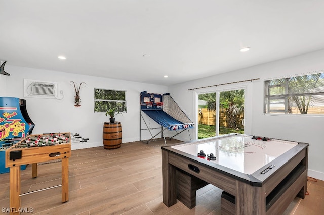 playroom featuring a wall mounted AC and light hardwood / wood-style floors