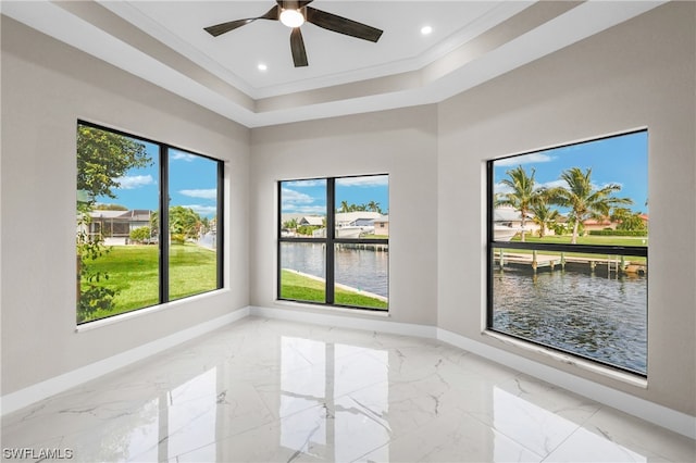 empty room featuring a raised ceiling, crown molding, a water view, and ceiling fan