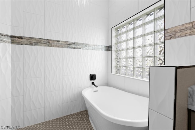 bathroom with a bathtub, tile patterned floors, and tile walls