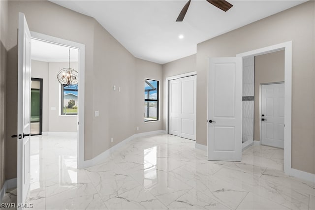 unfurnished bedroom with ceiling fan with notable chandelier and multiple windows