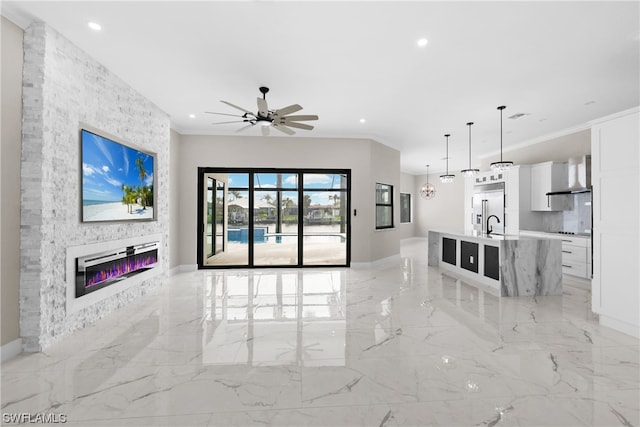 unfurnished living room with ceiling fan, a fireplace, sink, and ornamental molding