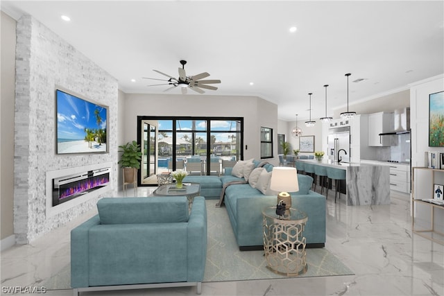 living room with a stone fireplace, ceiling fan, and ornamental molding