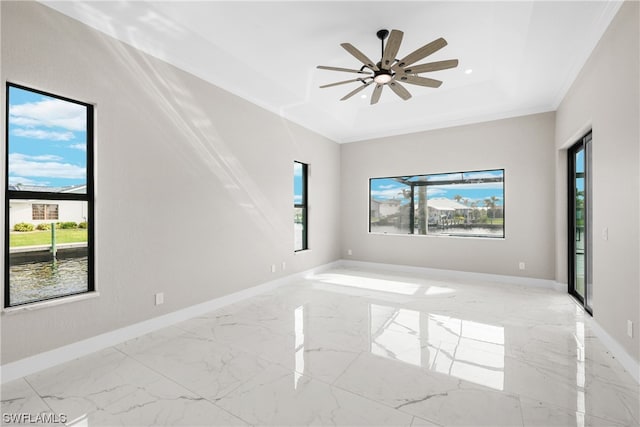 unfurnished room with a raised ceiling, ceiling fan, a healthy amount of sunlight, and ornamental molding