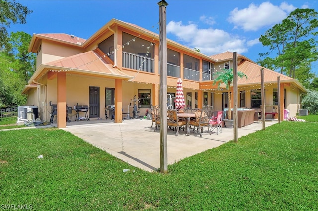 rear view of house with a yard, a balcony, central air condition unit, and a patio