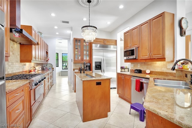 kitchen featuring pendant lighting, stainless steel appliances, backsplash, light stone counters, and an inviting chandelier