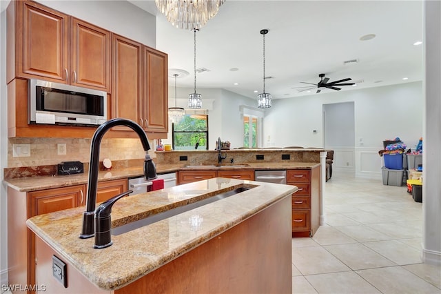 kitchen featuring appliances with stainless steel finishes, backsplash, light stone countertops, decorative light fixtures, and ceiling fan with notable chandelier