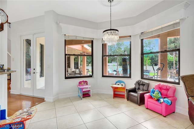 recreation room with an inviting chandelier, french doors, a wealth of natural light, and light tile floors