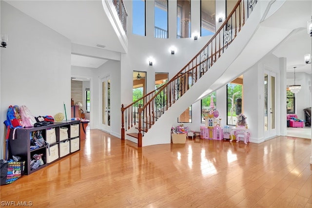 interior space featuring a towering ceiling, a chandelier, and light wood-type flooring