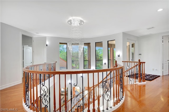 corridor with light hardwood / wood-style floors and a notable chandelier