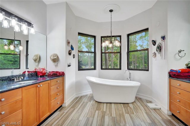 bathroom with a notable chandelier, a bathing tub, and oversized vanity