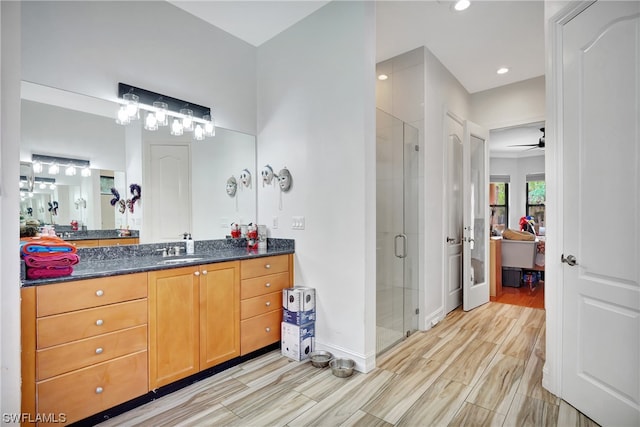 bathroom featuring a shower with door, vanity with extensive cabinet space, ceiling fan, and hardwood / wood-style flooring