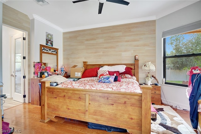 bedroom with light hardwood / wood-style floors, ornamental molding, and ceiling fan