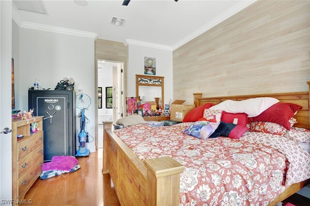 bedroom featuring wood walls, ornamental molding, ceiling fan, and light wood-type flooring