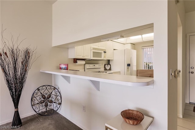 kitchen with white cabinetry, white appliances, a kitchen breakfast bar, and kitchen peninsula