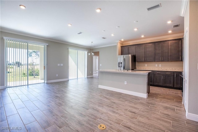 kitchen with crown molding, dark brown cabinets, a notable chandelier, a center island with sink, and stainless steel fridge with ice dispenser