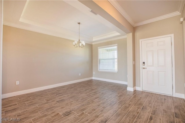 spare room featuring crown molding, a raised ceiling, and a chandelier