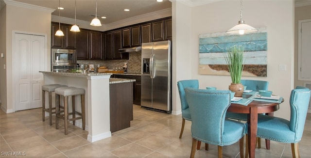 kitchen with crown molding, an island with sink, pendant lighting, stainless steel appliances, and light stone countertops