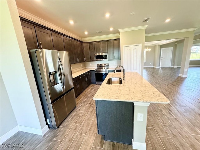 kitchen with dark brown cabinetry, stainless steel appliances, sink, and an island with sink