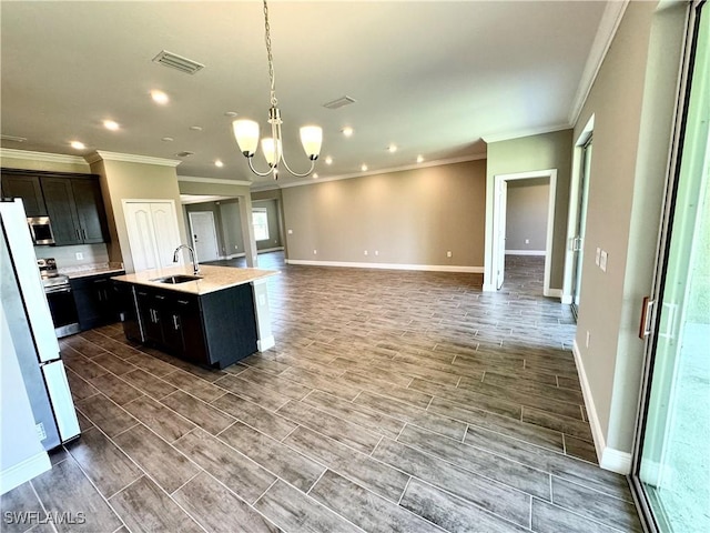 kitchen featuring sink, decorative light fixtures, a chandelier, a center island with sink, and stainless steel appliances