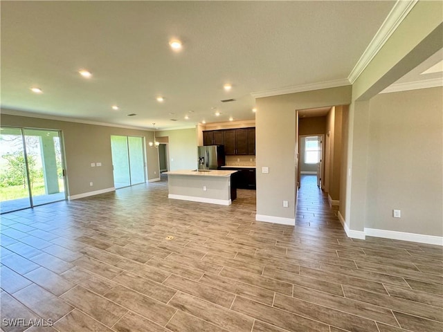 unfurnished living room featuring an inviting chandelier, ornamental molding, and a wealth of natural light