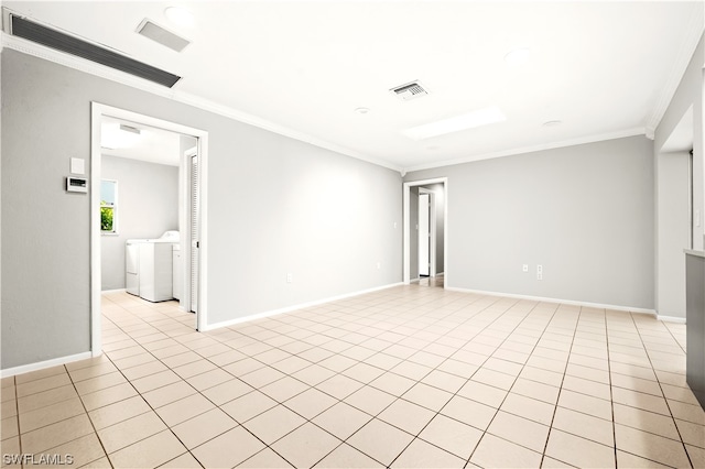 empty room with ornamental molding, light tile floors, and washing machine and clothes dryer