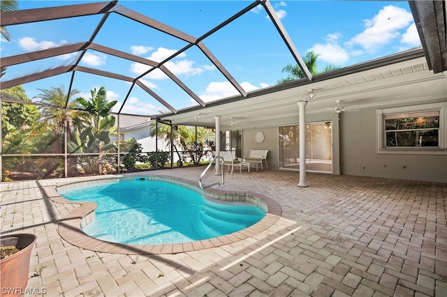 view of swimming pool with ceiling fan, a lanai, and a patio