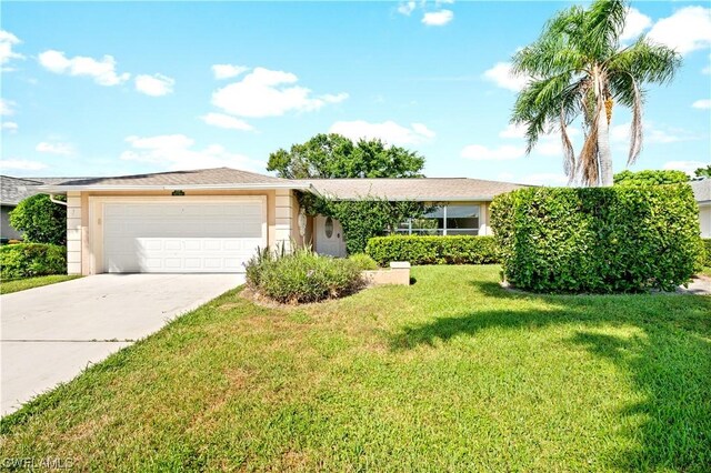 ranch-style home featuring a garage and a front lawn