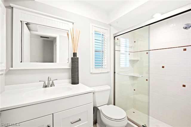 bathroom featuring vanity, toilet, and a shower with shower door