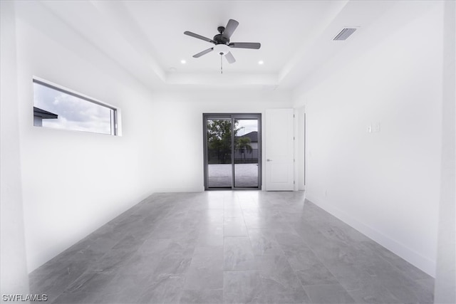 spare room featuring light tile floors, a tray ceiling, and ceiling fan