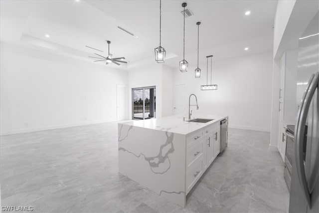 kitchen with pendant lighting, sink, light stone counters, a center island with sink, and white cabinetry